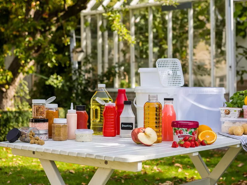 Picknickbord med plastflaskor och plastburkar för livsmedel