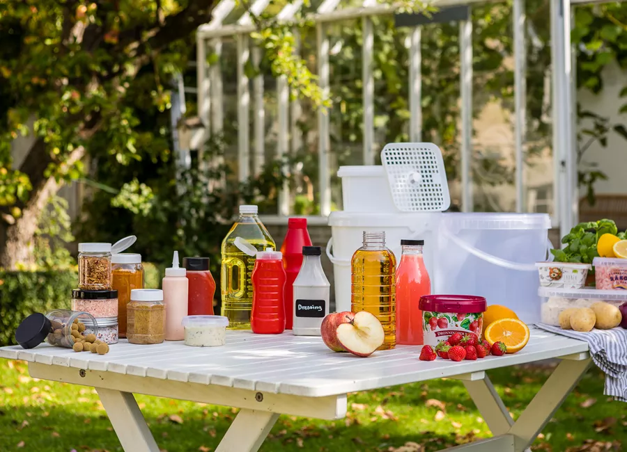 Picknickbord med plastflaskor och plastburkar för livsmedel